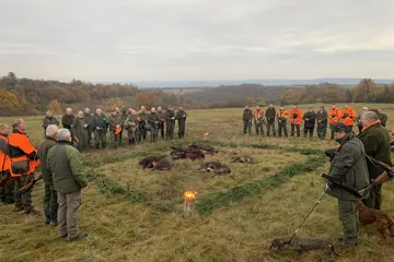 Poľovníci a vodiči psov okolo výlože na lúke nad Hontom
